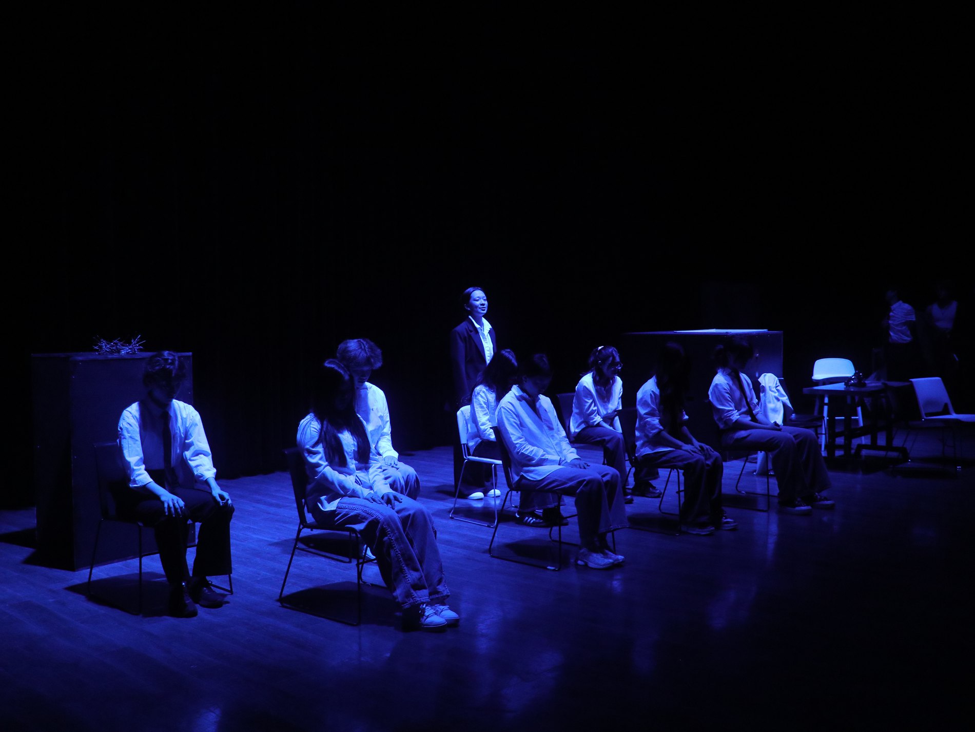 Ensemble in blue light on the set of Dead Poets Society, seated in a circle of chairs