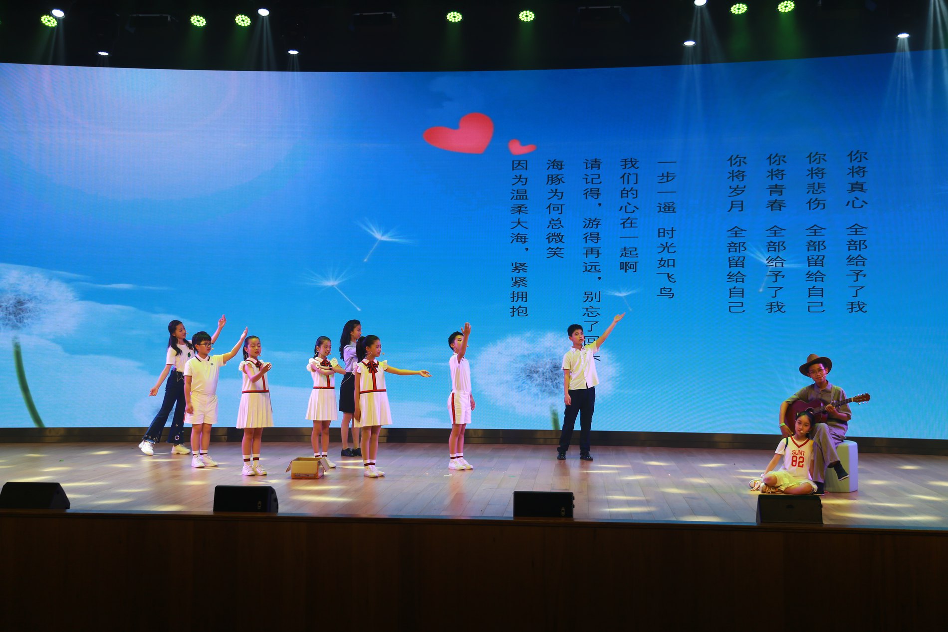 Ensemble on stage under a projected heart graphic
