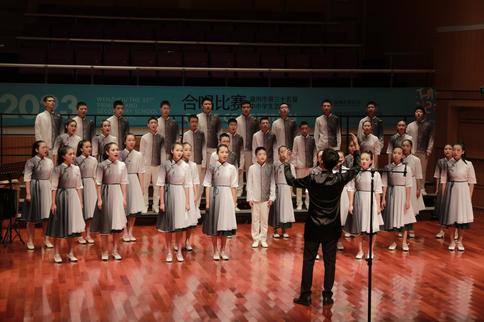 A large school choir performing in a concert hall