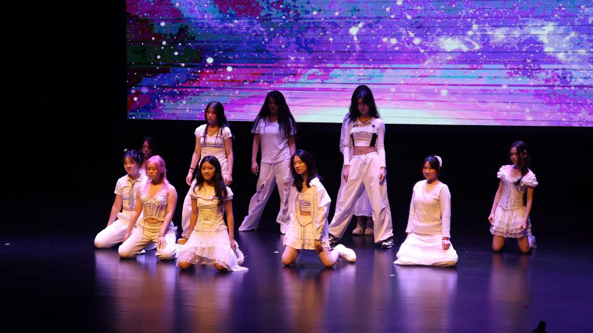 Dance ensemble performing on a lit stage